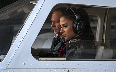 Young girl about to fly a plane with an instructor next to her.